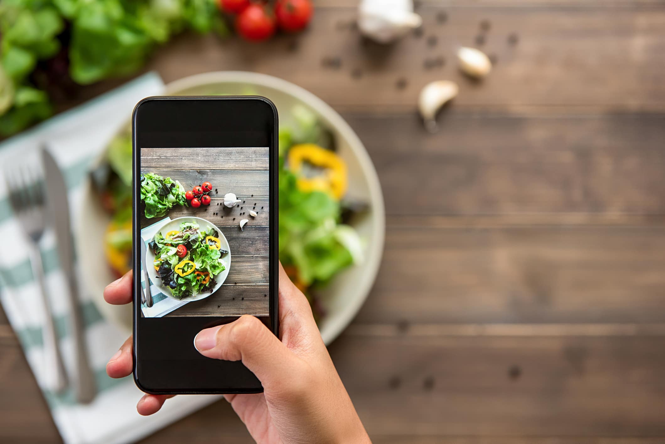 Food blogger using smartphone taking photo of beautiful mix fresh green salad