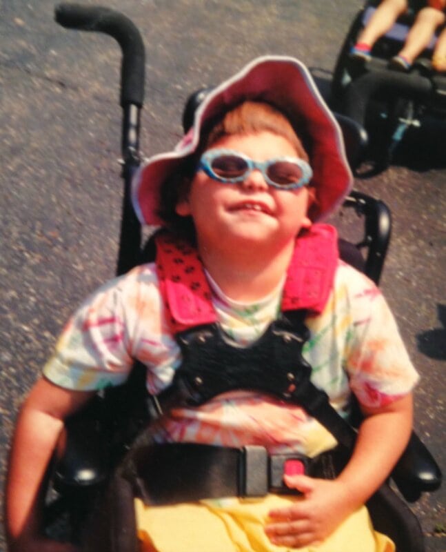 Little Bailey happily sitting on her wheelchair.