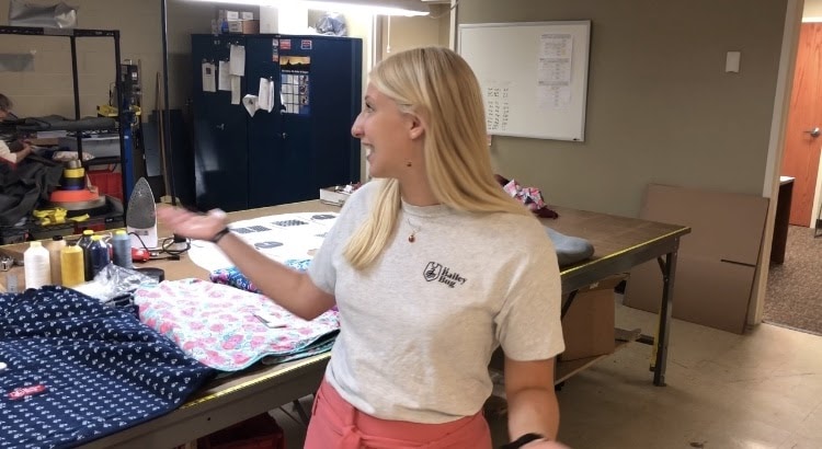 Melanie Barrett in the TAC workshop showing the fabrics behind her.