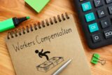 The text Workers Compensation written on a brown notepad.