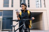 Young courier checking delivery address on smartphone.