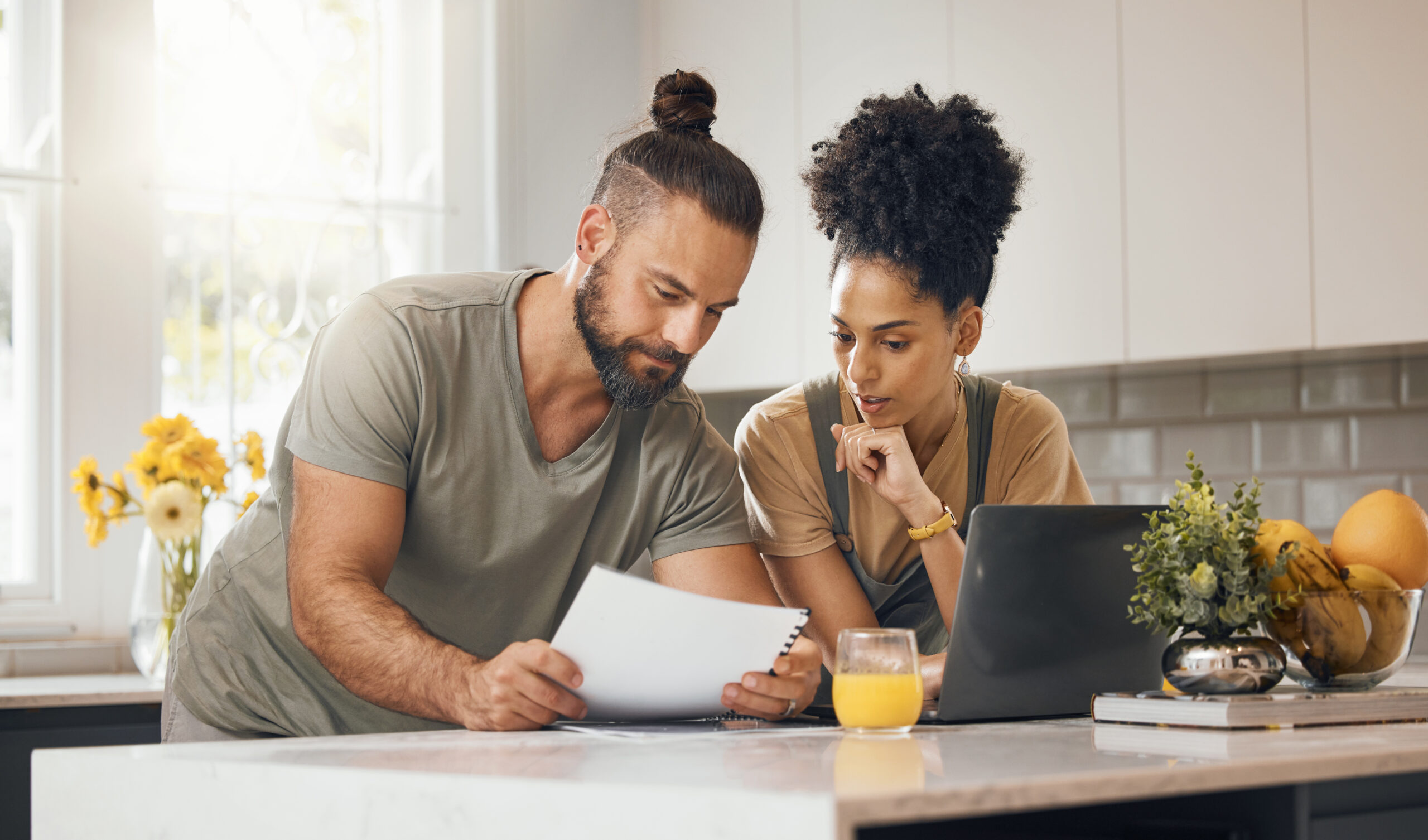 Man and woman reviewing documents in front of a computer in a kitchen