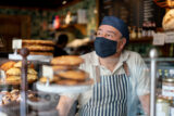 Portrait of a man working at a coffee shop wearing a face mask to avoid the coronavirus pandemic