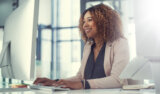 Smiling woman works at computer in office