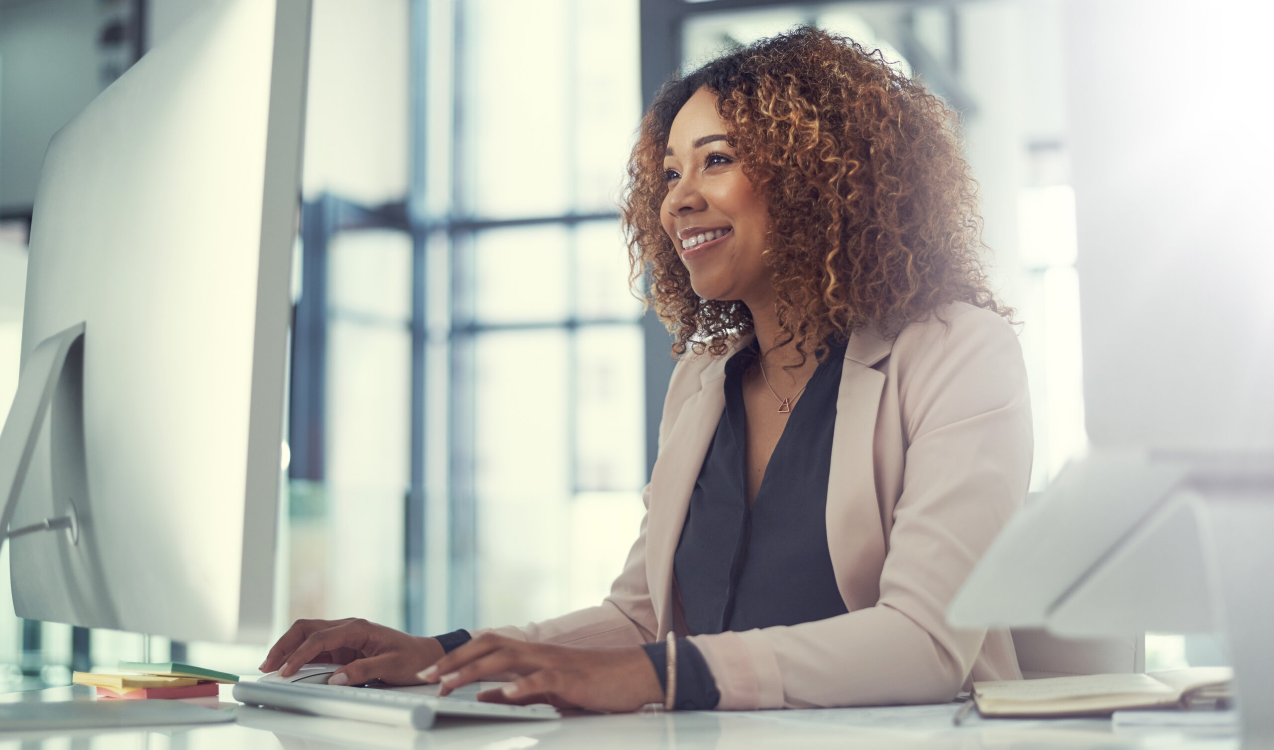 Smiling woman works at computer in office