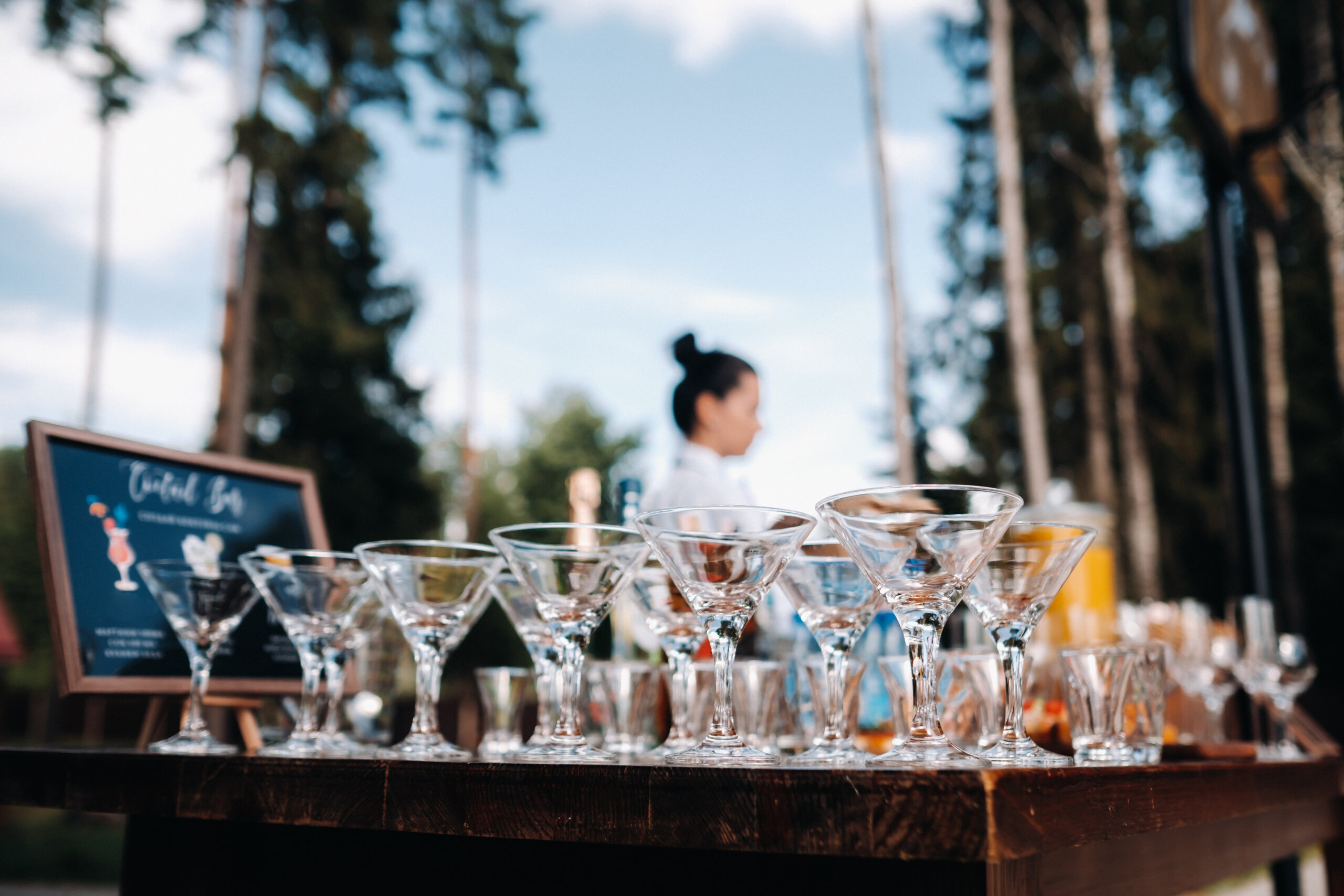 Rows of empty cocktail glasses on a table at an outdoor event