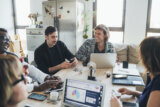 Smiling coworkers collaborate around a table